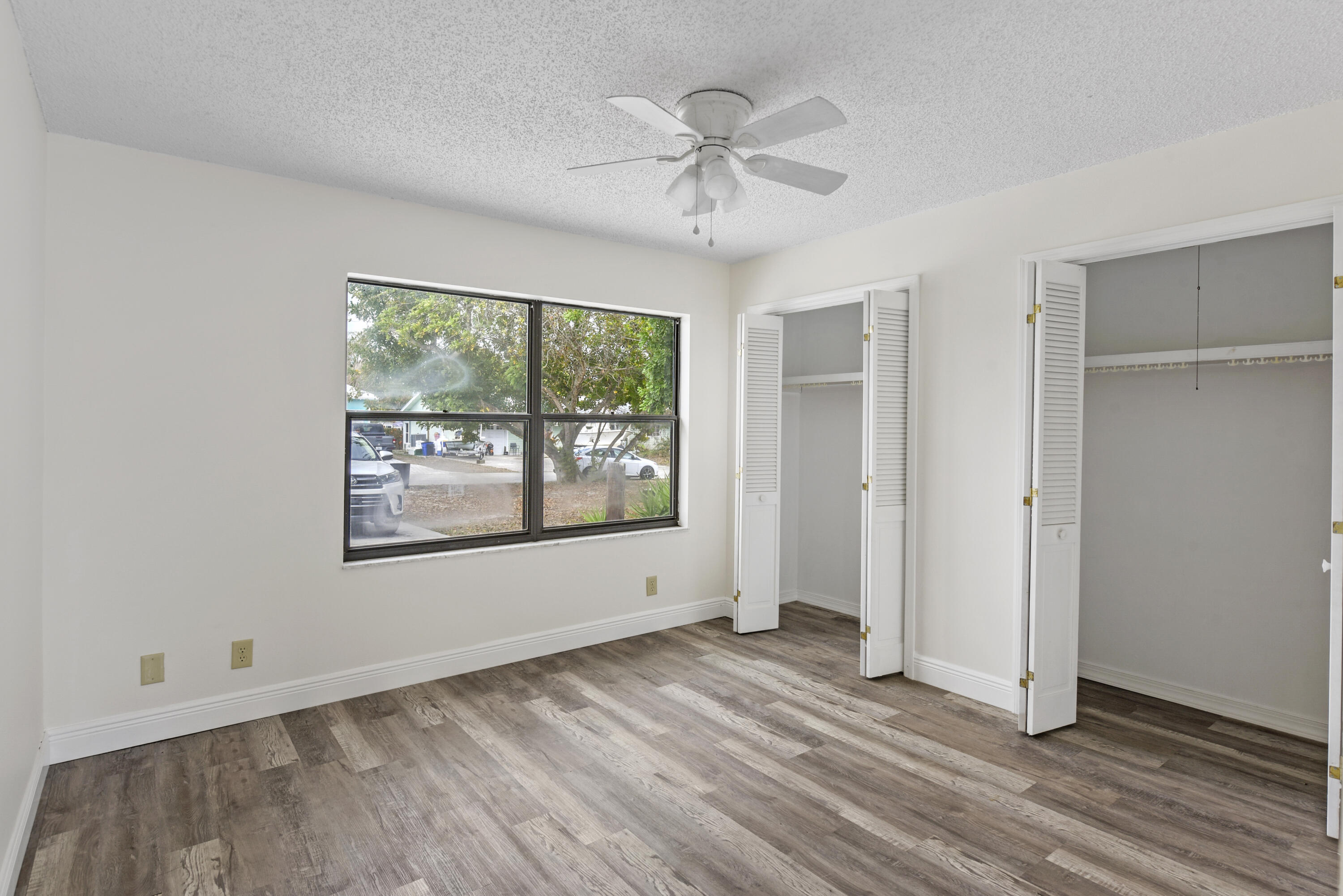 5666 Southeast Matousek Street Stuart, FL 34997 - Photo 14 of 49 an empty room with wooden floor chandelier fan and windows
