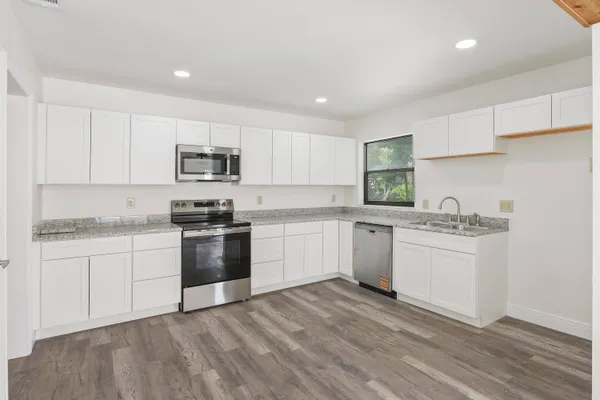 a kitchen with granite countertop white cabinets and stainless steel appliances