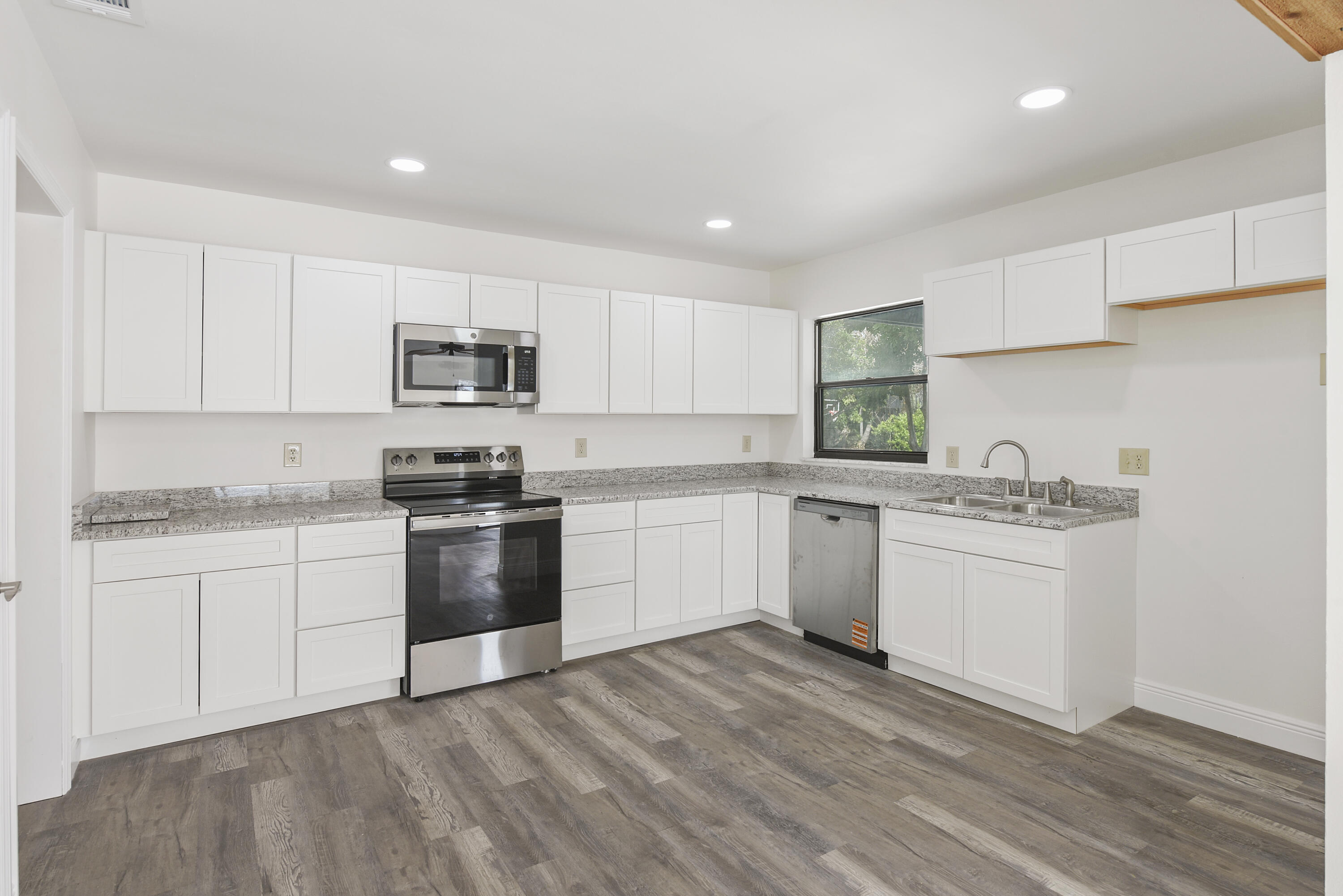 5666 Southeast Matousek Street Stuart, FL 34997 - Photo 2 of 49 a kitchen with granite countertop white cabinets and stainless steel appliances