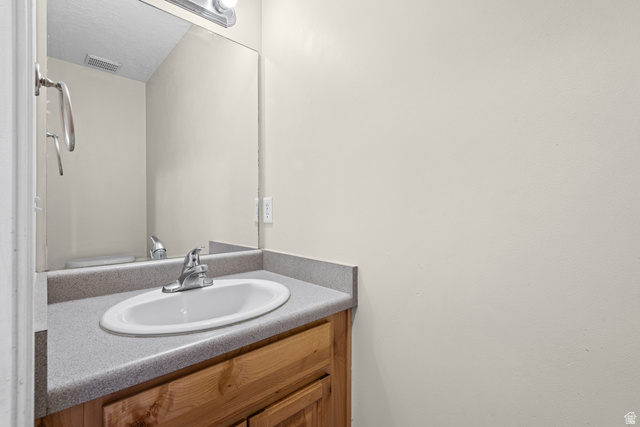 652 West 800 North, Unit 45 Clinton, UT 84015 - Photo 12 of 17 Vanity featuring a wood-finish base, integrated countertop with an oval sink, and a chrome faucet