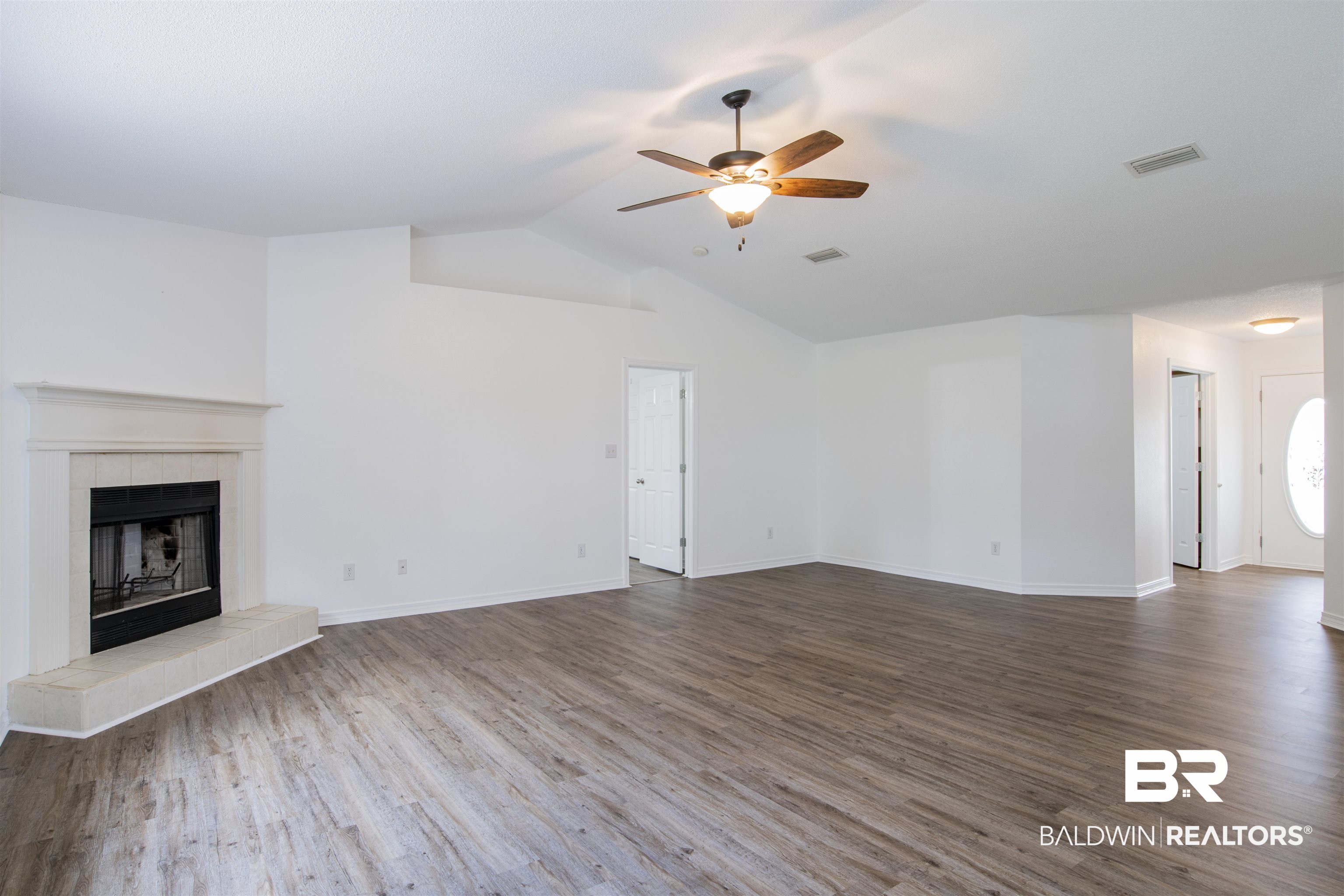 165 Pemberton Loop Fairhope, AL 36532 - Photo 9 of 25 Unfurnished living room with lofted ceiling, dark wood finished floors, visible vents, a tiled fireplace, and ceiling fan