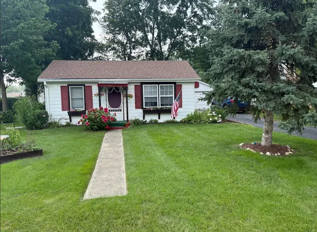 a front view of a house with a garden and trees