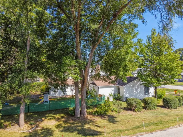 a backyard of a house with large trees and outdoor seating