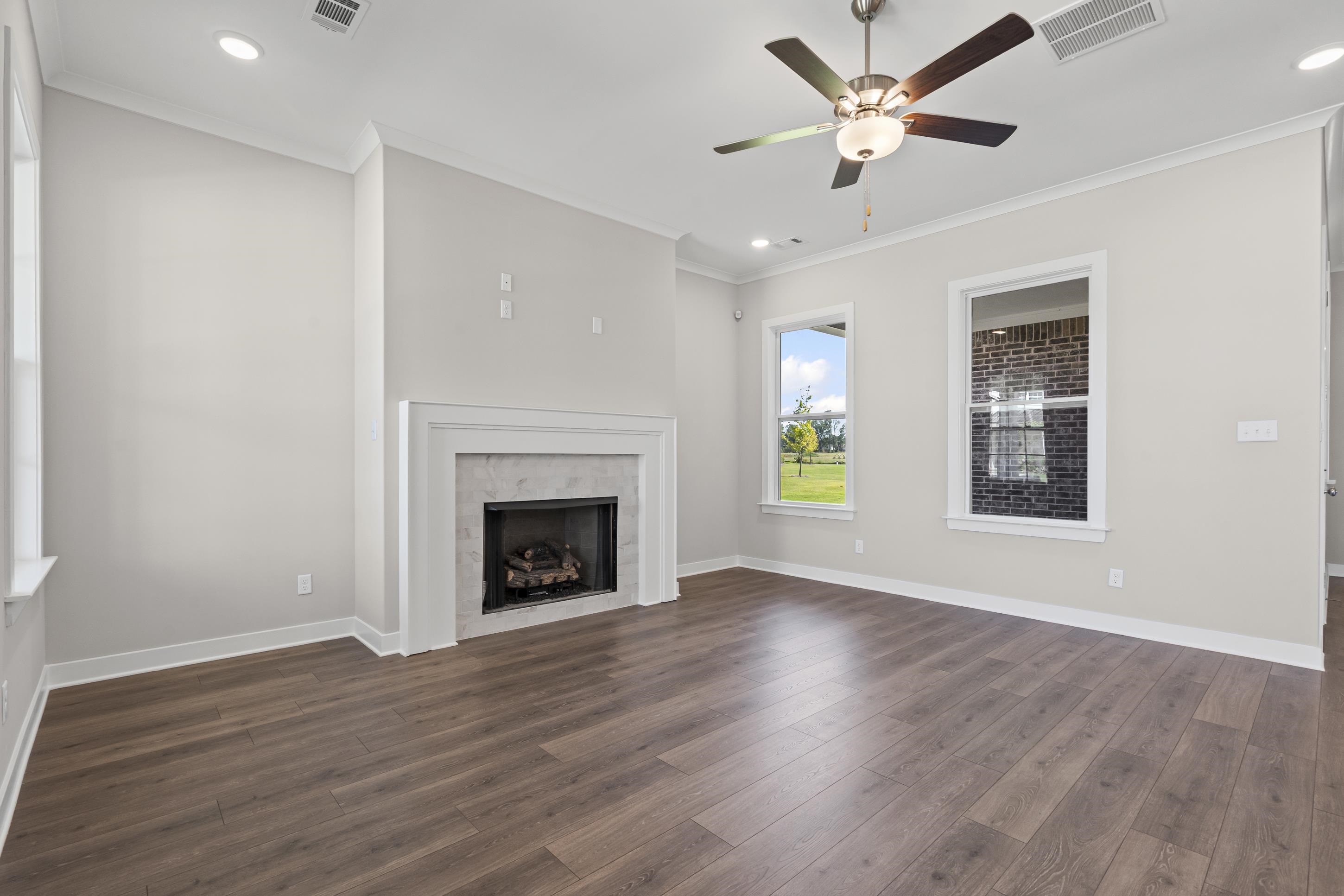 4824 Lyla Lane Collierville, TN 38017 - Photo 10 of 32 an empty room with wooden floor a ceiling fan and a fireplace