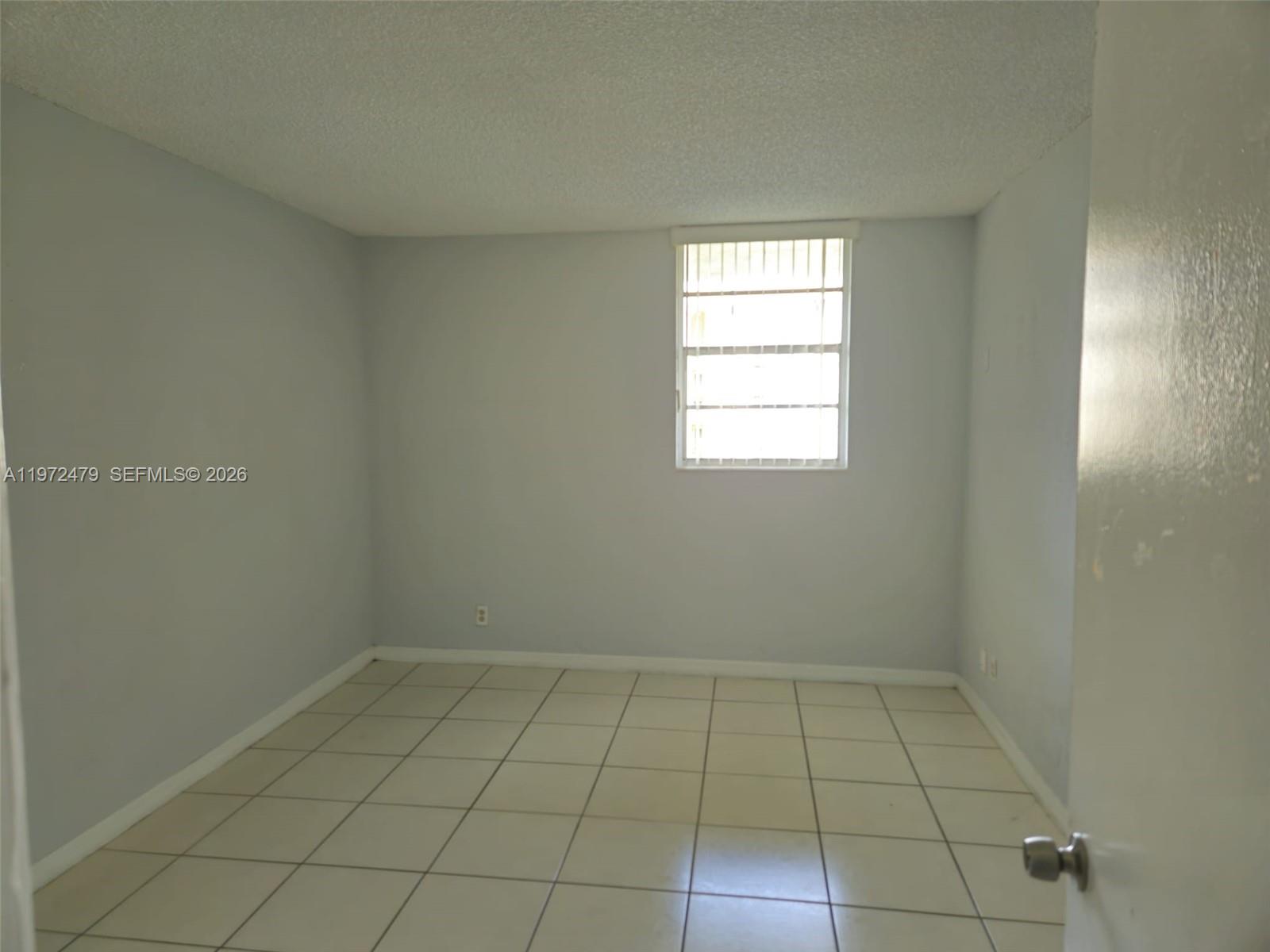 4550 Northwest 9th Street, Unit 704E Miami, FL 33126 - Photo 6 of 21 an empty room with a white cabinet and tiles