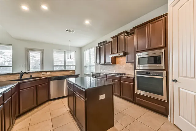 a kitchen with stainless steel appliances granite countertop a stove a sink and a refrigerator