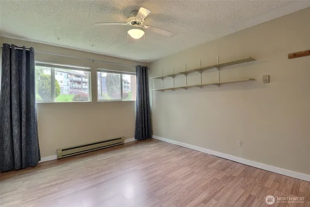 a view of an empty room with a window and wooden floor