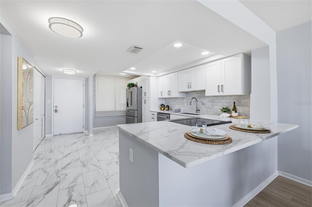 9495 Blind Pass Road, Unit 905 St. Pete Beach, FL 33706 - Photo 12 of 59 a kitchen with stainless steel appliances granite countertop a sink a stove a refrigerator and white cabinets