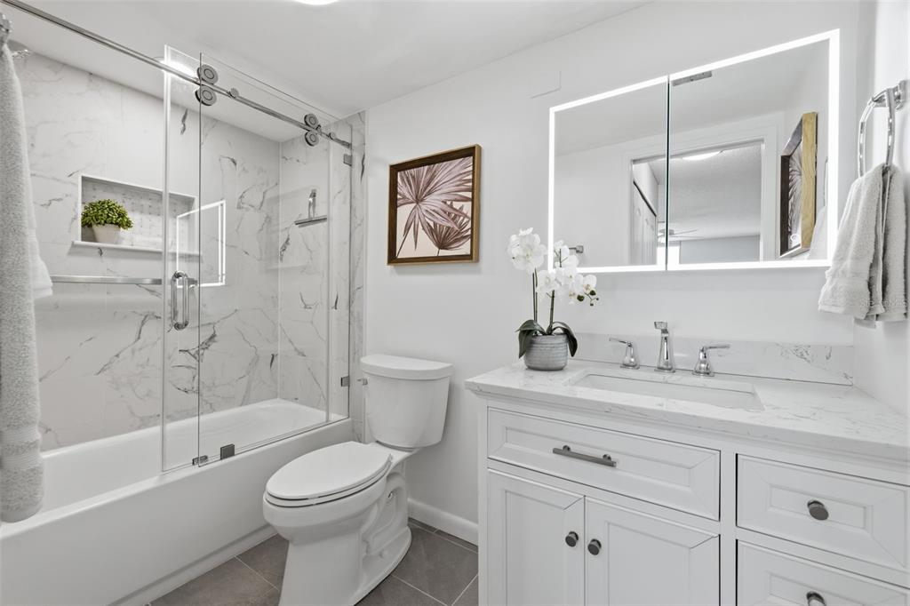 9495 Blind Pass Road, Unit 905 St. Pete Beach, FL 33706 - Photo 16 of 59 a bathroom with a granite countertop toilet a sink and a bathtub