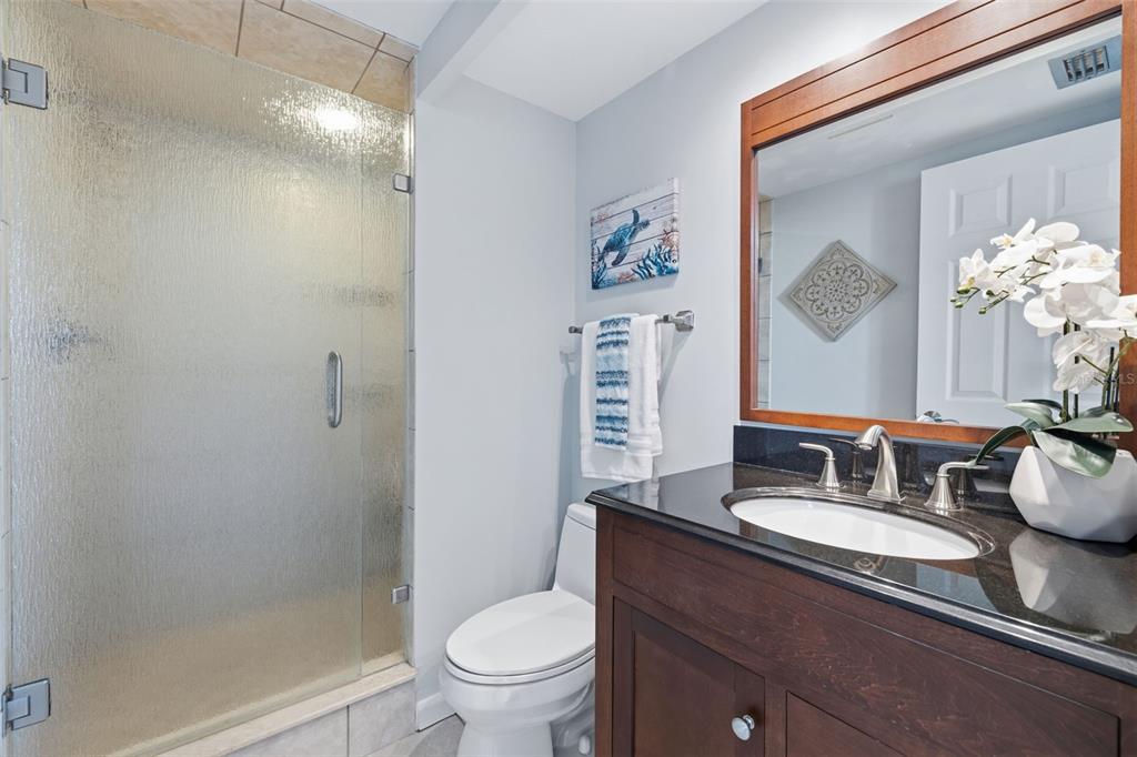 9495 Blind Pass Road, Unit 905 St. Pete Beach, FL 33706 - Photo 20 of 59 a bathroom with a granite countertop sink toilet and a mirror