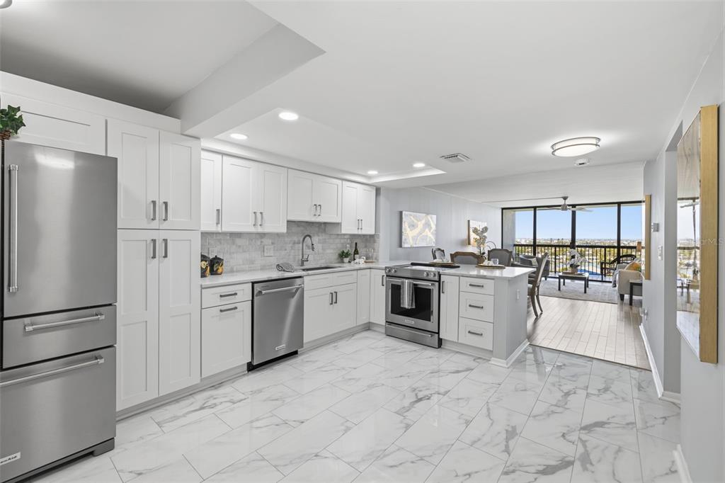 9495 Blind Pass Road, Unit 905 St. Pete Beach, FL 33706 - Photo 4 of 59 a kitchen with granite countertop cabinets and white stainless steel appliances