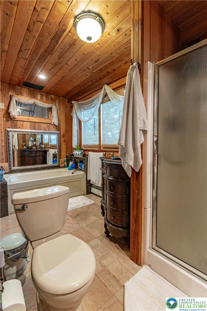 2485 Hieter Road Quakertown, PA 18951 - Photo 33 of 97 Natural wood paneling and large windows define this comfortable bathing space, featuring a built-in tub and separate shower.