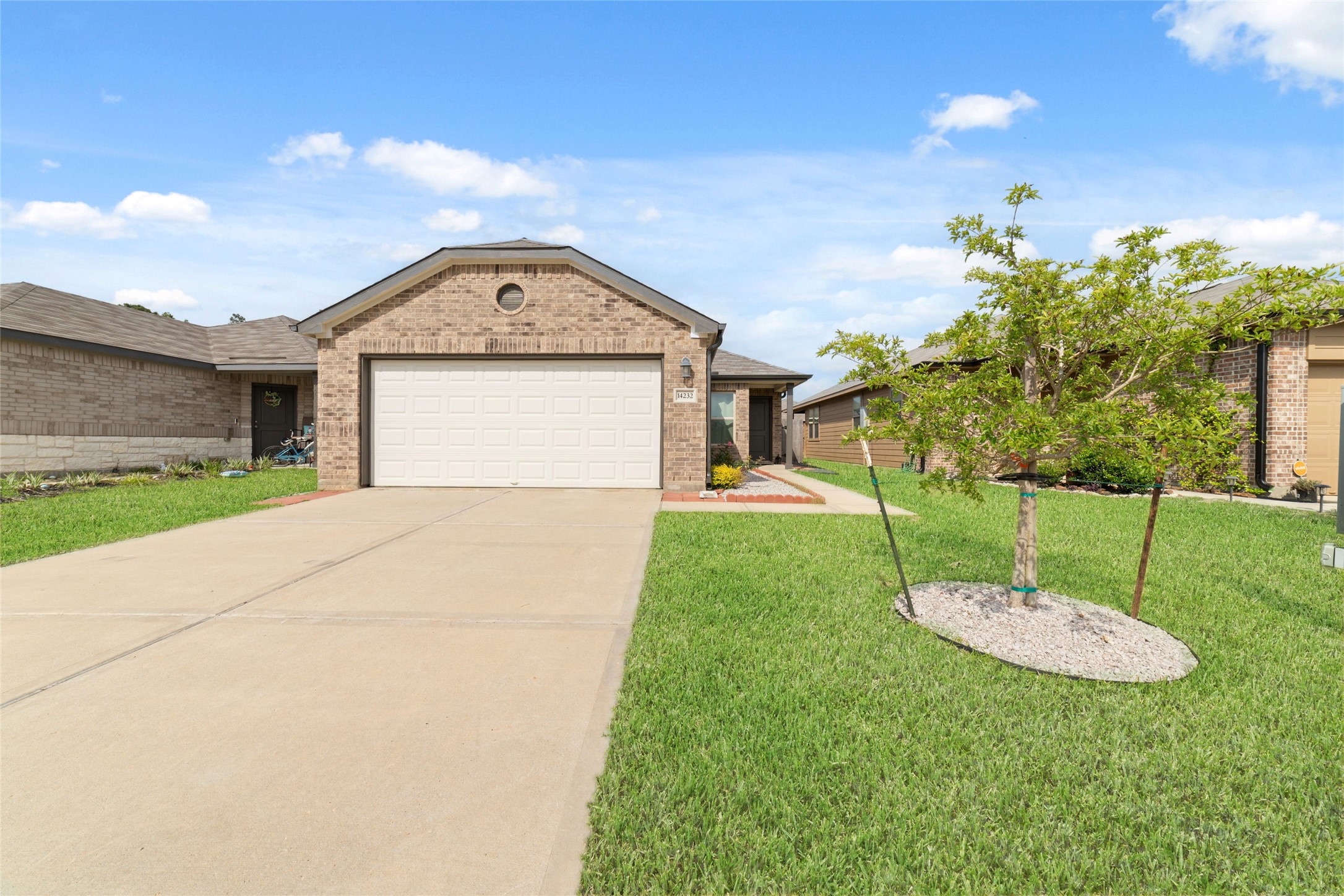 Charming brick exterior with a wide driveway and well-kept lawn, creating a welcoming first impression.