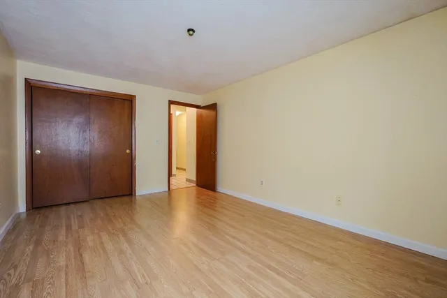 a view of an empty room with wooden floor and closet