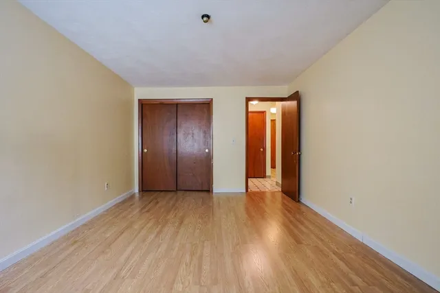 a view of an empty room with wooden floor and closet