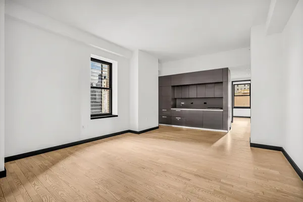 a view of an empty room with a kitchen and a window