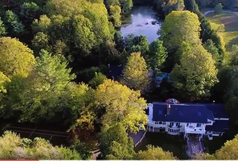 an aerial view of a house with a yard and a large tree