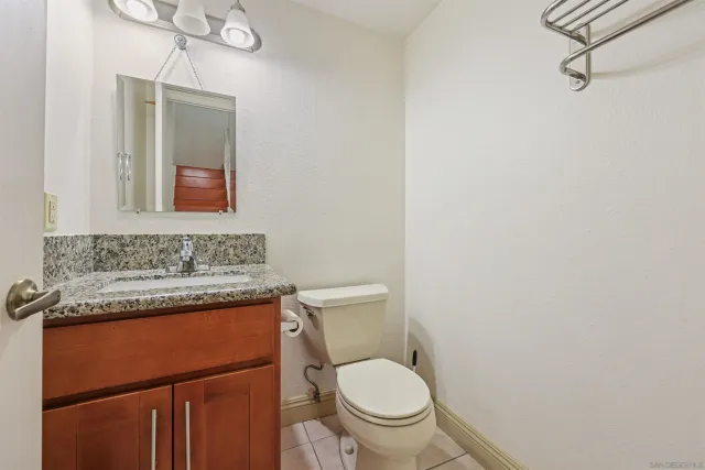 a bathroom with a granite countertop toilet sink and mirror