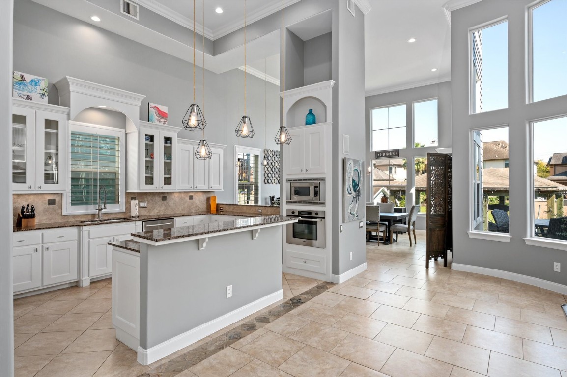 211 Valmar Street Kemah, TX 77565 - Photo 27 of 50 a kitchen with stainless steel appliances kitchen island granite countertop a stove and a refrigerator