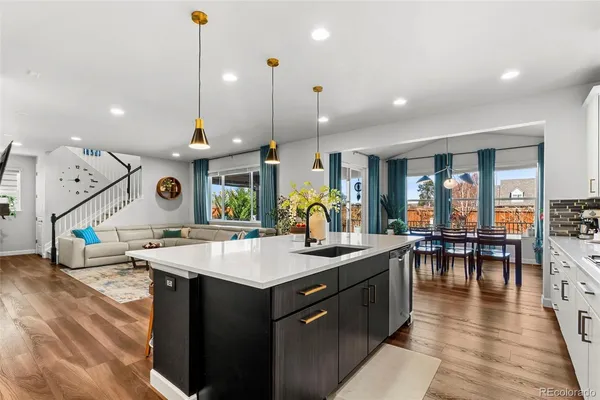 a kitchen with stainless steel appliances kitchen island granite countertop a stove a sink a dining table and chairs with wooden floor