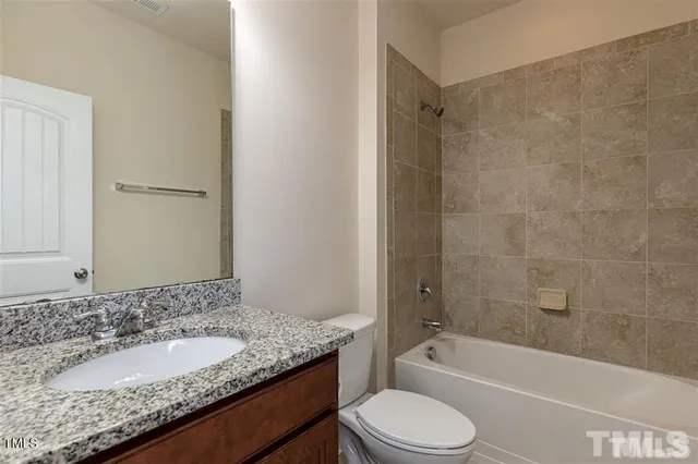 a bathroom with a granite countertop bathtub shower sink vanity mirror and toilet