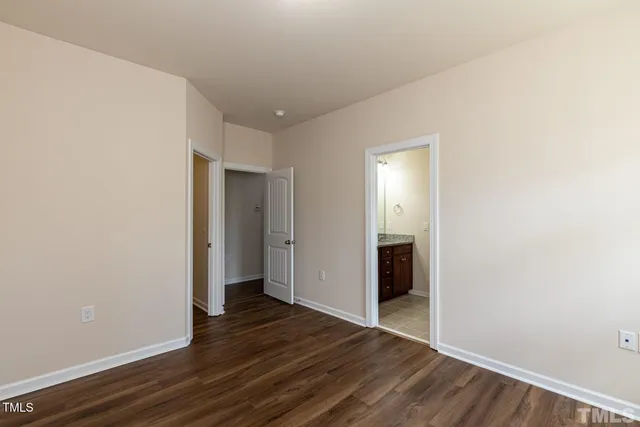 a view of an empty room with wooden floor and closet