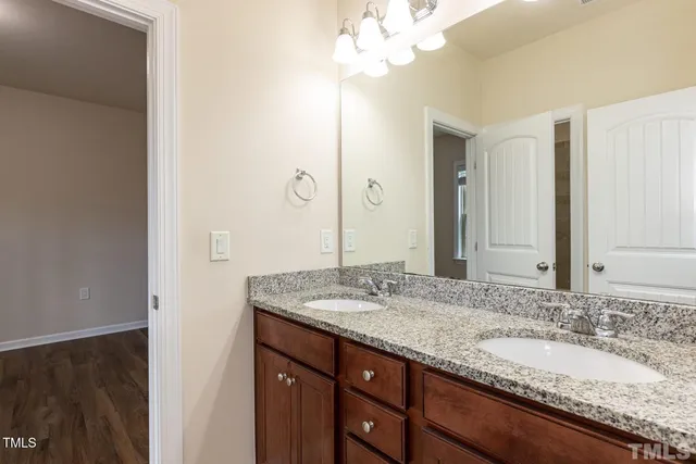 a bathroom with a granite countertop double vanity sink and mirror