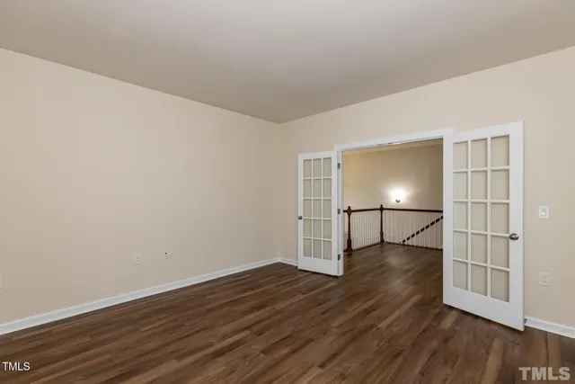 an empty room with wooden floor fireplace and windows