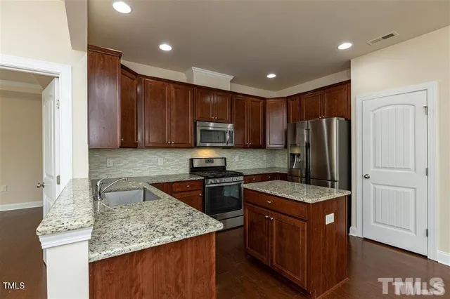 a kitchen with kitchen island granite countertop stainless steel appliances sink stove microwave and cabinets