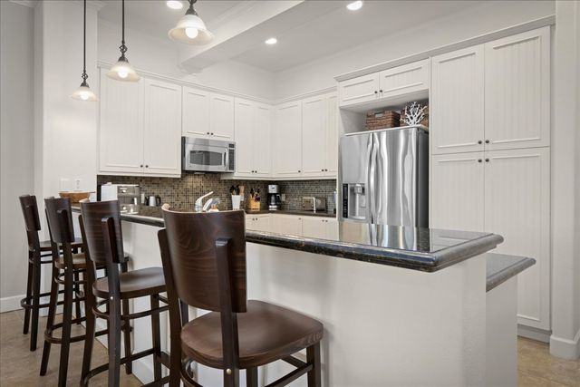 a kitchen with stainless steel appliances granite countertop a stove a refrigerator a sink a dining table and chairs