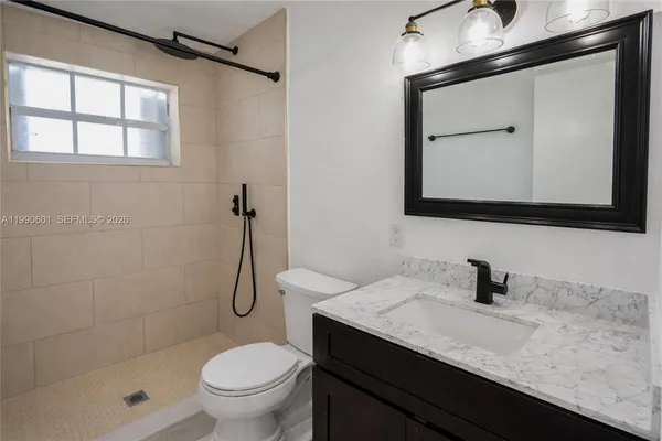 a bathroom with a granite countertop sink a toilet and shower