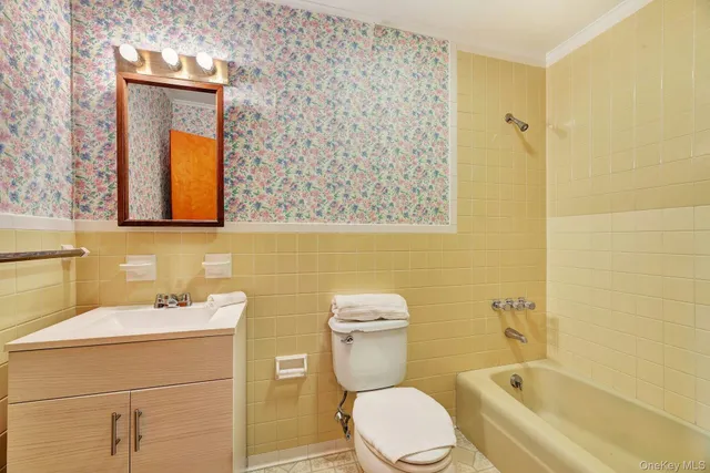a bathroom with a toilet sink vanity tub and mirror