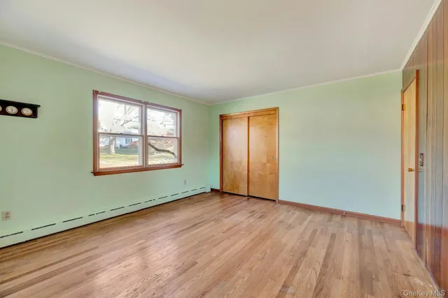 an empty room with wooden floor closet and windows