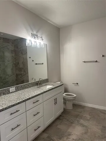 a bathroom with a granite countertop sink a toilet and a mirror
