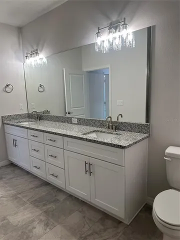 a bathroom with a granite countertop sink a toilet and a mirror
