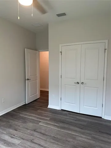an empty room with wooden floor & closet area
