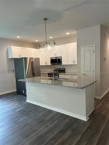 a view of kitchen with stainless steel appliances granite countertop counter space and wooden floors