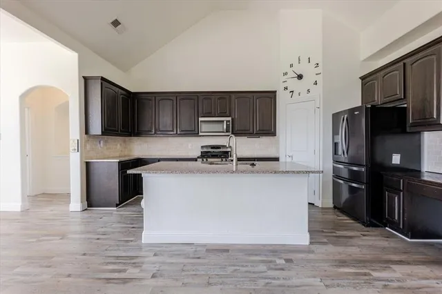 a kitchen with stainless steel appliances granite countertop a stove top oven a refrigerator a sink and dishwasher