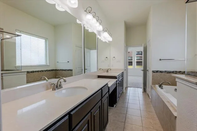 a spacious bathroom with a granite countertop sink a large mirror and a bathtub
