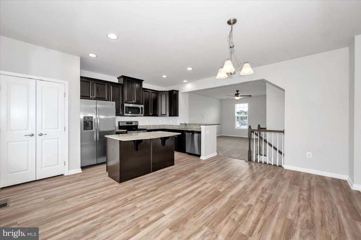 105 Montreal Way Falling Waters, WV 25419 - Photo 19 of 53 a kitchen with stainless steel appliances granite countertop a refrigerator a sink dishwasher a stove and a dining table with wooden floor