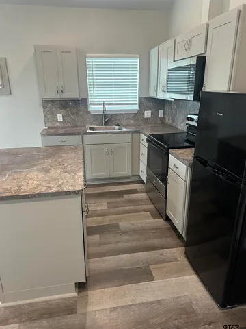 a kitchen with granite countertop a sink stove and cabinets