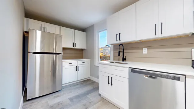 a kitchen with appliances a refrigerator a sink and cabinets