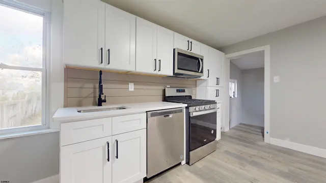a kitchen with white cabinets stainless steel appliances and sink