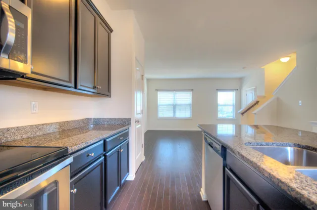 a kitchen with granite countertop a sink a stove and cabinets