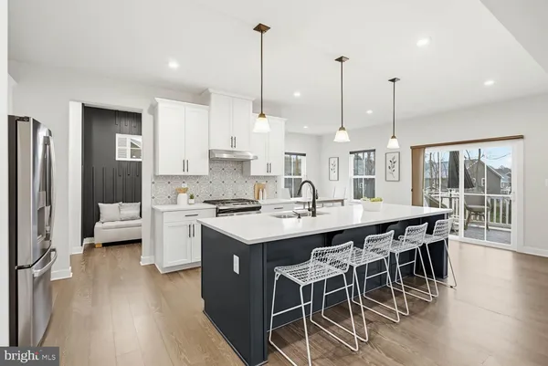 a kitchen with stainless steel appliances kitchen island granite countertop a table chairs and a wooden floors