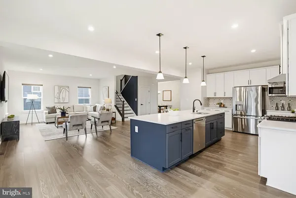 a large kitchen with stainless steel appliances a large counter top a sink a stove and a wooden floor