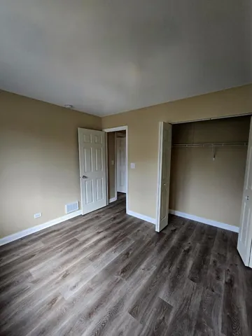 a view of an empty room with wooden floor and closet