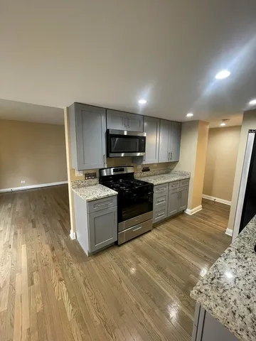 a large kitchen with cabinets wooden floor and stainless steel appliances