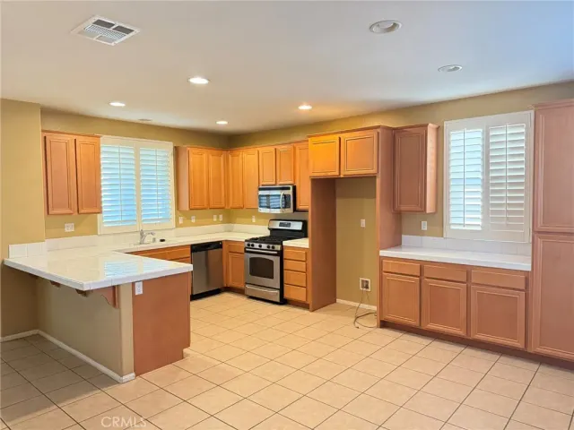 a kitchen with stainless steel appliances granite countertop a refrigerator a sink a stove top oven and a refrigerator