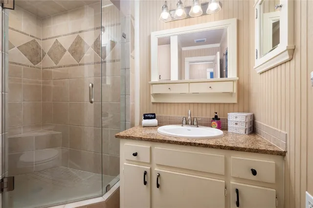 a bathroom with a granite countertop sink a mirror and shower